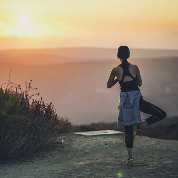 Woman performing yoga on hill